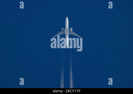 Un avion blanc volant à 40,000 pieds dans le ciel bleu pendant une journée ensoleillée au-dessus de l'Europe, un vol pendant une journée d'hiver claire. L'illustration du symbole de l'avion à grand-corps survolant sans logo imprimé sur le dessous du ventre du fuselage laisse derrière lui des contrailles ou un sentier de condensation, une ligne de vapeur blanche. L'industrie de l'aviation et le trafic de passagers sont en phase de phase avec une période difficile avec la pandémie du coronavirus Covid-19 ayant un impact négatif sur l'industrie du voyage d'affaires avec la crainte d'une aggravation de la situation en raison de la nouvelle mutation de la variante Omega. Eindhoven, pays-Bas sur D. Banque D'Images