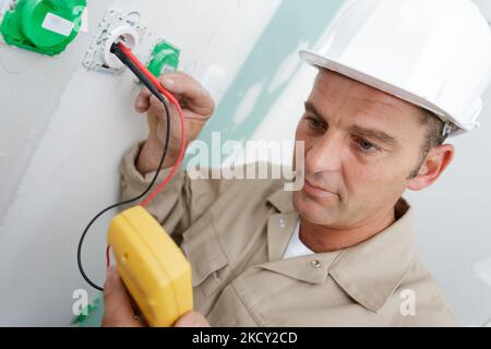 un électricien assemble une prise murale bipolaire standard Banque D'Images