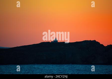 Silhouette d'une petite église au sommet de la colline au-dessus de la mer pendant le coucher du soleil. Les touristes apprécient un beau coucher de soleil pendant l'heure magique à l'île de Mykonos en Grèce. L'île grecque de Myconos est une destination prisée de voyage en Méditerranée pour des vacances dans les Cyclades, la mer Égée avec les bâtiments emblématiques blanchis à la chaux, les plages de sable et la célèbre fête aux bars de plage. L'industrie du tourisme et du voyage a eu un impact négatif dans le secteur des affaires et de l'économie locale en raison de la pandémie du coronavirus Covid-19. Île de Mykonos, Grèce sur 10 octobre 2021 (photo de Nicolas Economou/NurPh Banque D'Images