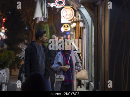 Un iranien et une femme regardent une vitrine tout en marchant le long d'une rue dans la ville d'Ispahan, à 450 km (281 miles) au sud de Téhéran, la nuit sur 14 décembre 2021. Un porte-parole de l'Université des sciences médicales d'Ispahan a déclaré : « selon la dernière coloration épidémique de la maladie de Covid-19, la métropole d'Ispahan était dans un état bleu (à faible risque), qui est proportionnel à la diminution du nombre de tests coronariens positifs et de personnes hospitalisées. » Selon une nouvelle de l'Agence iranienne de nouvelles des étudiants (ISNA). (Photo de Morteza Nikoubazl/NurPhoto) Banque D'Images