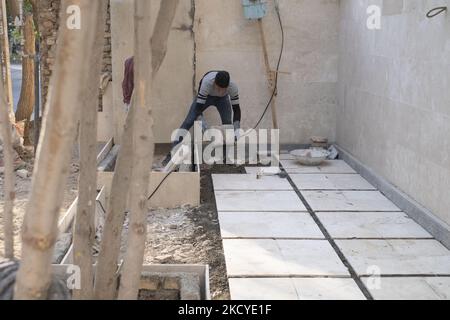 Fereydoun Ahmadi-26, réfugié afghan et champion du monde de kickboxing, Qui doit travailler en tant que travailleur de la construction pour recueillir de l'argent pour les frais de subsistance, travaille dans un immeuble résidentiel qui est actuellement en construction, dans la région de Mehrshahr à l'ouest de la ville de Karaj dans la province d'Alborz 53km (33 milles) nord-ouest de Téhéran sur 10 octobre 2021. Fereydoun est champion du monde de kickboxing et sa femme Masoumeh est également instructeur de kickboxing, qui sont tous deux afghans et sont nés en Iran, souhaitant un jour qu'ils puissent vivre en paix dans un pays qui les accepte comme ses citoyens. (Photo Banque D'Images