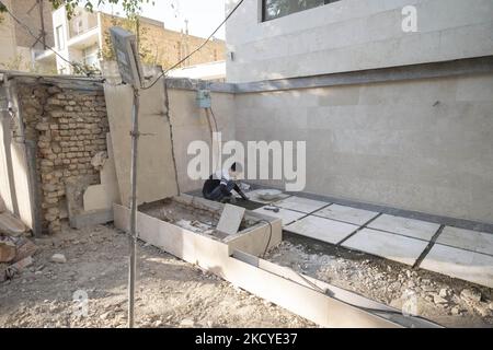 Fereydoun Ahmadi-26, réfugié afghan et champion du monde de kickboxing, Qui doit travailler en tant que travailleur de la construction pour recueillir de l'argent pour les frais de subsistance, travaille dans un immeuble résidentiel qui est actuellement en construction, dans la région de Mehrshahr à l'ouest de la ville de Karaj dans la province d'Alborz 53km (33 milles) nord-ouest de Téhéran sur 10 octobre 2021. Fereydoun est champion du monde de kickboxing et sa femme Masoumeh est également instructeur de kickboxing, qui sont tous deux afghans et sont nés en Iran, souhaitant un jour qu'ils puissent vivre en paix dans un pays qui les accepte comme ses citoyens. (Photo Banque D'Images