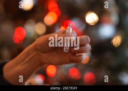 Une femme effectue un test rapide d'antigène COVID-19 devant l'arbre de Noël avant de rejoindre sa famille pour le dîner de la veille de Noël. Le dispositif de test rapide de l'antigène COVID-19 à réponse rapide détecte la présence d'antigènes nucléoprotéiques viraux du COV-SRAS-2 dans les sécrétions nasales et nasopharyngées. En seulement 15 minutes, les individus peuvent déterminer un résultat positif ou négatif. Vendredi, 24 décembre 2021, à Edmonton, en Alberta, Canada. (Photo par Artur Widak/NurPhoto) Banque D'Images