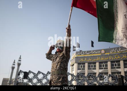 Un iranien qui a peint son visage comme un drapeau de l'Iran portant un uniforme du corps des Gardiens de la révolution islamique (IRGC) salue tout en portant un drapeau de l'Iran lors d'un rassemblement sur la place Imam Hussein au sud-est de Téhéran sur 30 décembre 2021. Les partisans du Guide suprême de l'Iran, l'ayatollah Ali Khamenei, assistent à un rassemblement pour marquer l'anniversaire des manifestations anti-opposition du 2009 décembre à Téhéran. (Photo de Morteza Nikoubazl/NurPhoto) Banque D'Images