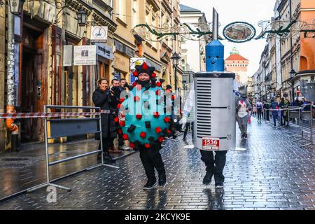 Des personnes vêtues de costumes drôles du modèle Covid-19 et d'une seringue avec une vaccination assistent à la traditionnelle course du nouvel an de Cracovie 17th dans la vieille ville de Cracovie, en Pologne, sur 31 décembre 2021. (Photo de Beata Zawrzel/NurPhoto) Banque D'Images