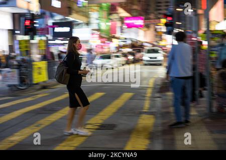 Une dame portant un masque rose traverse la rue à Mongkok dans un coup de pans, à Hong Kong, Chine, 2 janvier 2022. (Photo de Marc Fernandes/NurPhoto) Banque D'Images