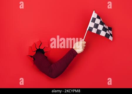 drapeau à carreaux en main sur fond rouge Banque D'Images