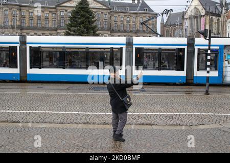 Une femme prend un selfie près de la place du Dam. Les habitants et quelques touristes dans les rues calmes d'Amsterdam pendant le confinement dans la capitale néerlandaise avec des magasins et des magasins paraissant avec fermé avec le roller métal volet vers le bas, cafés, bars et restaurants également fermés avec des tables et des chaises des terrasses fermées. Les pays-Bas ont été la première nation européenne à déclarer un verrouillage complet pour lutter contre la nouvelle variante d'Omicron qui s'intensifie. Après une commande soudaine du gouvernement avant Noël, le pays a fermé tous les magasins, cafés, restaurants, bars, salles de sport, écoles, lieux sportifs, lieux culturels a Banque D'Images