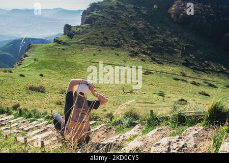 Femme s'étendant sur des marches de pierre dans les montagnes. Détendez-vous en grimpant jusqu'au sommet, surplombant les montagnes environnantes avec de l'herbe verte Banque D'Images