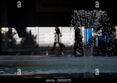 Les gens portant un masque protégé passent près d'une fontaine dans le centre d'Athènes, en Grèce, sur 15 janvier 2022. (Photo de Nikolas Kokovovlis/NurPhoto) Banque D'Images