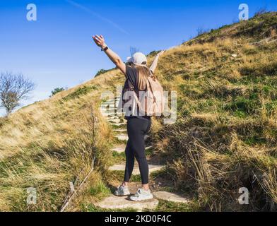 Femme randonneur debout avec ses bras sur son chemin vers le haut. Conception conceptuelle. Femme touriste à bras ouverts pendant le soleil couchant. Fille avec un revers Banque D'Images