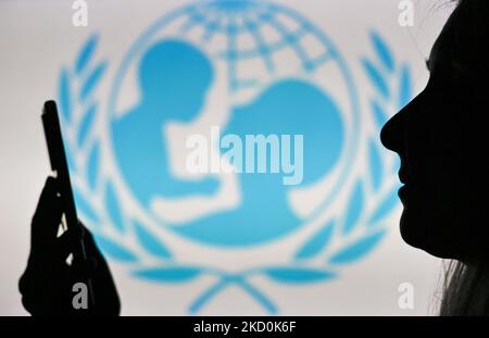 Image d'une femme tenant un téléphone portable devant le logo de l'UNICEF affiché sur un écran d'ordinateur. Mardi, 12 janvier 2021, à Edmonton, en Alberta, Canada. (Photo par Artur Widak/NurPhoto) Banque D'Images