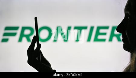 Image d'une femme tenant un téléphone portable devant le logo Frontier Airlines affiché sur un écran d'ordinateur. Mardi, 12 janvier 2021, à Edmonton, en Alberta, Canada. (Photo par Artur Widak/NurPhoto) Banque D'Images