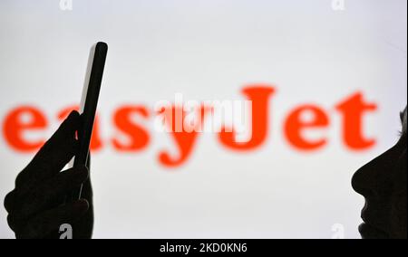 Image d'une femme tenant un téléphone portable devant le logo easyJet affiché sur un écran d'ordinateur. Mardi, 12 janvier 2021, à Edmonton, en Alberta, Canada. (Photo par Artur Widak/NurPhoto) Banque D'Images
