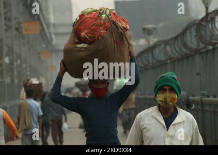 Un ouvrier travailliste transporte des légumes qui passe devant le pont de howrah dans une matinée brumeuse au-dessus du fleuve Ganga, dans le cadre d'une urgence du coronavirus à 21 janvier 2022 à Kolkata, dans le Bengale occidental, en Inde. (Photo de Debajyoti Chakraborty/NurPhoto) Banque D'Images