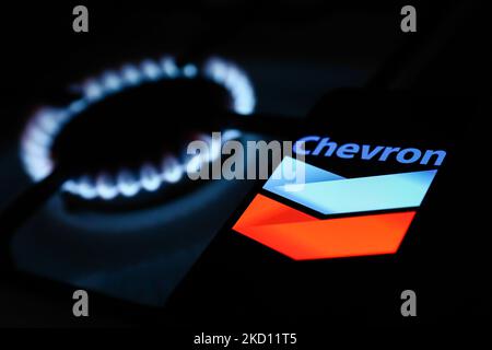 Les flammes d'un brûleur à gaz et le logo Chevron affichés sur l'écran d'un téléphone sont visibles sur cette photo d'illustration prise à Cracovie, en Pologne, sur 22 janvier 2022. (Photo de Jakub Porzycki/NurPhoto) Banque D'Images