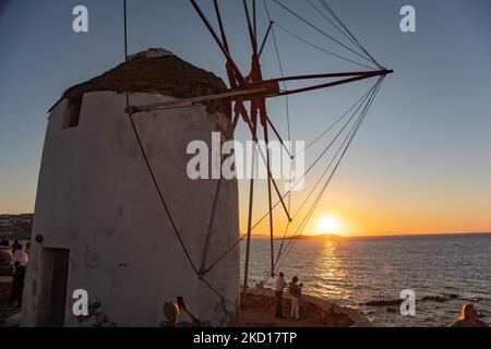 Coucher de soleil sur les moulins à vent emblématiques de l'île de Mykonos dans les îles Cyclades avec le soleil juste au-dessus de l'horizon au-dessus de la mer. Mykonos est une île en Grèce, dans la mer Égée. Il y a 16 moulins à vent sur l'île, dont 5 au-dessus de Chora, la ville principale de l'île. Les moulins à vent ont été construits au 16th siècle à partir des Vénitiens mais leurs constructions se sont poursuivies jusqu'au 20th siècle. Coucher de soleil avec les gens aux moulins à vent de Mykonos. Les touristes apprécient un beau coucher de soleil pendant l'heure magique à l'île de Mykonos en Grèce. L'île grecque de Myconos est une destination de voyage populaire et glamour en Méditerranée Banque D'Images