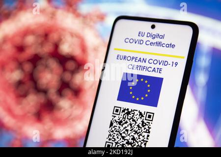 Illustration photo d'une main tenant et montrant l'affichage d'un téléphone portable avec un certificat de vaccination numérique européen Covid-19 avec un QR, un certificat de vaccination international ou un passe sanitaire avec une illustration du virus Covid et un ADN / ARN sur le fond. Photo sur le sujet des faux certificats de vaccination. Actuellement, la propagation de la pandémie se fait sur la cinquième vague du coronavirus, la mutation omicron étant la variante dominante. Amsterdam, pays-Bas sur 25 janvier 2022 (photo de Nicolas Economou/NurPhoto) Banque D'Images