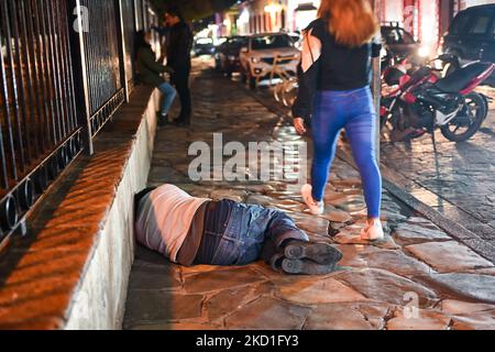 Une femme passe devant un homme dormant sur le chemin dans le centre de San Cristobal de las Casas. Samedi, 29 janvier 2022, à San Cristobal de las Casas, Chiapas, Mexique. (Photo par Artur Widak/NurPhoto) Banque D'Images