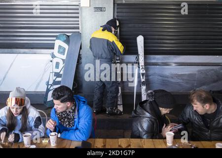 Les jeunes iraniens s'interparlent alors qu'un skieur place son équipement de ski près d'un mur dans un restaurant de restauration rapide au bas d'une pente dans la station de ski Darbandsar, à 67Km (42 miles) au nord-est de Téhéran, sur 28 janvier 2022. Malgré la prévalence de la variante Omicron de la nouvelle coronavirus (COVID-19) en Iran, La ville de Téhéran n'est toujours pas dans une situation rouge (à haut risque) et les gens peuvent encore s'amuser et skier sur les pistes de ski. Mais selon le dernier rapport de l'Agence de presse métropolitaine d'Iran (IMNA), dans la nouvelle situation de la prévalence de la variation Omicron de Covid-19 en Iran, Banque D'Images