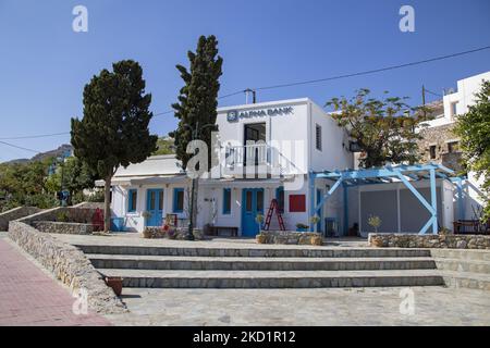 Un beau bâtiment blanchi à la chaux d'Alpha Bank. Livadia, le port et le village principal de l'île de Tilos avec les maisons à l'architecture traditionnelle blanchie à la chaux et la plage avec l'eau de mer cristalline. Telos est une petite île grecque méditerranéenne située dans la partie de la mer Égée des îles Dodécanèse avec une population de 780 habitants près de la côte turque. Fin 2018, Tilos est devenue la première île de la Méditerranée à fonctionner exclusivement sur l'énergie éolienne et solaire, une île verte autosuffisante, une initiative financée par l'UE pour l'énergie verte provenant de sources renouvelables protégeant l'environnement naturel. Banque D'Images