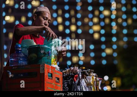 Coffee Street vendor sans masque facial protecteur comme mesure de précaution contre l'épidémie de coronavirus marcher sur une route généralement occupée dans le quartier des affaires de Jakarta le 3 février 2022. Depuis l'annonce des cinq premiers patients Omicron sur 16 décembre 2021, jusqu'à la fin janvier 2022, les cas de la nouvelle variante COVID-19 en Indonésie ont continuellement augmenté après un bref déclin après la deuxième vague en juin-juillet 2021. En date du mercredi 26 janvier, quelque 1 988 patients infectés par le virus Omicron ont été enregistrés. Le nombre quotidien de cas de COVID-19 avait atteint 9 905 à vendredi, 28 janvier. Le ministre de la Santé Budi Gunadi Sadikin estima Banque D'Images