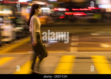 Une jeune femme masquée traverse une rue à Mongkok dans ce plan panoramique, à Hong Kong, en Chine, sur 5 février 2022, À Hong Kong, en Chine, sur 5 février 2022. (Photo de Marc Fernandes/NurPhoto) Banque D'Images