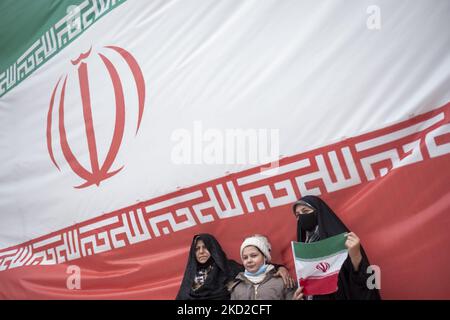 Une famille iranienne se tient sous le drapeau géant de l’Iran tout en assistant à un rassemblement pour marquer 43rd ans de victoire de la révolution islamique iranienne de 1979 sur la place Azadi (liberté) à l’ouest de Téhéran, au milieu de l’apparition de la variante Omicron du COVID-19 en Iran, sur 11 février 2022. L'Iran connaît une nouvelle fois une augmentation du nombre de personnes infectées par le COVID-19 par la propagation de la variante Omicron. (Photo de Morteza Nikoubazl/NurPhoto) Banque D'Images