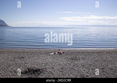 Journée ensoleillée et mer calme à la plage de Kohili, avec des galets tandis qu'une femme aime le soleil, près du village de Limni, une destination de voyage, avec la pente brûlée et la forêt en arrière-plan. Après les incendies en Grèce, une énorme catastrophe environnementale s'est produite dans le pays. À l'endroit précis de la rive, une évacuation avec un traversier a eu lieu en août, alors que l'incendie a entouré la région. Forêt, pins, oliveraies, entreprises, hôtels, le camping, les maisons, les véhicules et les animaux ont été brûlés. Le feu s'est terminé après une nuit de pluie, alors que les jours précédents les pompiers grecs, le volun local Banque D'Images