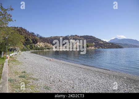 Journée ensoleillée et mer calme à la plage de Kohili, avec des galets tandis qu'une femme aime le soleil, près du village de Limni, une destination de voyage, avec la pente brûlée et la forêt en arrière-plan. Après les incendies en Grèce, une énorme catastrophe environnementale s'est produite dans le pays. À l'endroit précis de la rive, une évacuation avec un traversier a eu lieu en août, alors que l'incendie a entouré la région. Forêt, pins, oliveraies, entreprises, hôtels, le camping, les maisons, les véhicules et les animaux ont été brûlés. Le feu s'est terminé après une nuit de pluie, alors que les jours précédents les pompiers grecs, le volun local Banque D'Images