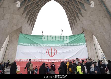 Le peuple iranien se tient devant un drapeau géant de l’Iran sous le monument Azadi (liberté) sur la place Azadi, à l’ouest de Téhéran, lors d’un rassemblement marquant le 43rd anniversaire de la victoire de la révolution islamique iranienne de 1979, au milieu de l’apparition de la variante Omicron du COVID-19 en Iran, Sur 11 février 2022. L'Iran connaît une nouvelle fois une augmentation du nombre de personnes infectées par le COVID-19 par la propagation de la variante Omicron. (Photo de Morteza Nikoubazl/NurPhoto) Banque D'Images