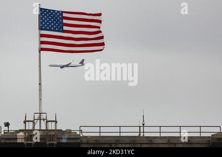 Le drapeau américain agitant sur la tour du pont de Brooklyn à New York City aux États-Unis, vu pendant une journée nuageux avec un avion de Delta Airlines. Le célèbre pont, un point de repère pour NYC et les États-Unis d'Amérique est un pont suspendu hybride à câbles qui enjambe l'East River entre les quartiers de Manhattan et Brooklyn. Le pont historique de New York a été construit entre 1869 et 1883. New York, Etats-Unis sur 13 février 2020 (photo de Nicolas Economou/NurPhoto) Banque D'Images