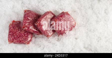 Viandes de bœuf en sachets sous vide sur glace sur fond blanc - Panorama Banque D'Images