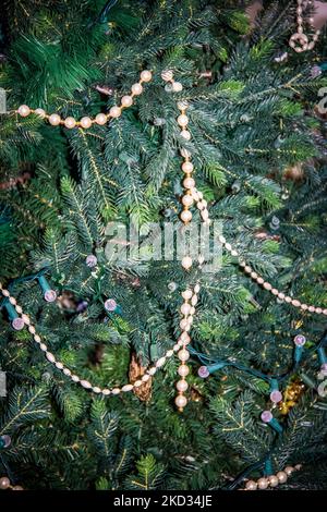 Gros plan d'un arbre de Noël artificiel avec quelques lumières et une piqûre de perles qui restent dessus - en train de descendre pour la saison Banque D'Images