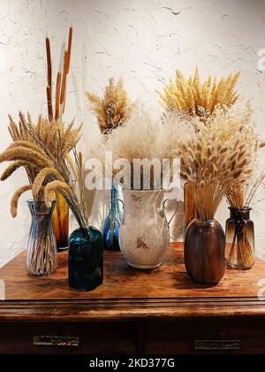 Composition avec de nombreuses fleurs séchées différentes dans des vases, sur un fond clair. Banque D'Images