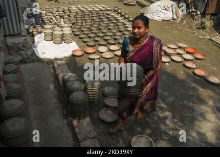 Une femelle potier arrange des ustensiles faits de boue d'argile pour sécher au soleil à Kumar Para (communauté de potters) dans la banlieue de Munshigonj de Dhaka, au Bangladesh sur 22 février 2022. (Photo de Kazi Salahuddin Razu/NurPhoto) Banque D'Images