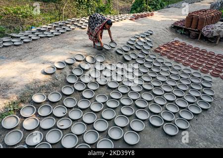 Une femelle potier arrange des ustensiles faits de boue d'argile pour sécher au soleil à Kumar Para (communauté de potters) dans la banlieue de Munshigonj de Dhaka, au Bangladesh sur 22 février 2022. (Photo de Kazi Salahuddin Razu/NurPhoto) Banque D'Images