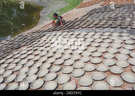 Une femelle potier arrange les ustensiles faits de boue d'argile à sécher au soleil à côté d'un étang Munshigonj banlieue de Dhaka, Bangladesh, 22 février 2022. (Photo de Kazi Salahuddin Razu/NurPhoto) Banque D'Images