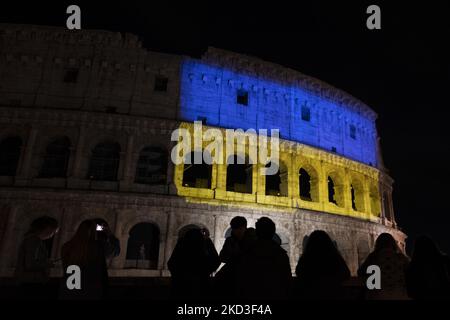 Les gens regardent le drapeau ukrainien sur le Colisée à Rome, Italie, sur 24 février 2022. Alors que le conflit en Ukraine s'intensifie, le drapeau ukrainien est montré dans de nombreuses capitales, dont Rome, qui a choisi de dépeindre le drapeau sur le Colussem. Rome 24th février 2022 (photo de Francesco Boscarol/NurPhoto) Banque D'Images