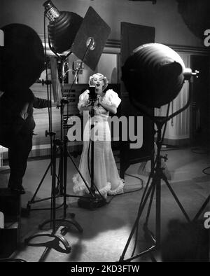 GRACE MOORE sur le plateau chantant candide au microphone pendant le tournage d'UNE NUIT D'AMOUR 1934 réalisateur VICTOR SCHERTZINGER cinéaste Joseph Walker costume design Robert Kalloch producteur Harry Cohn Columbia Pictures Banque D'Images