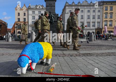 Les soldats américains de la division aéroportée de 82nd passent par une figure de mouton peinte dans les couleurs du drapeau ukrainien lors de leur visite sur la place principale de Cracovie, en Pologne, sur 8 mars 2022. Les troupes américaines sont arrivées en Pologne pour renforcer les divers alliés de l'OTAN en Europe de l'est, y compris en Pologne, au moment où l'invasion russe d'Ukrain a commencé. (Photo de Beata Zawrzel/NurPhoto) Banque D'Images