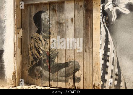 Street Art. Un garçon assis à pieds croisés, faisant partie d'une série de peintures murales sur une rangée de bâtiments dans la vieille ville de Lagos, Algarve, Portugal Banque D'Images