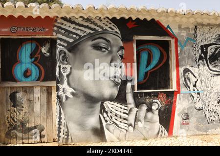 Street Art. Une fresque d'une femme africaine et d'un garçon assis en croix à pattes peintes sur un vieux bâtiment. Lagos, Algarve, Portugal Banque D'Images