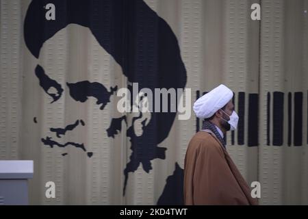 Un religieux iranien passe devant un graffiti à l'ayatollah Ruhollah Khomeini, fondateur et premier dirigeant spirituel de la République islamique d'Iran, dans la ville sainte de Qom 145km (90 miles) au sud de Téhéran sur 10 mars 2022. (Photo de Morteza Nikoubazl/NurPhoto) Banque D'Images