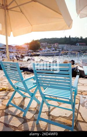 Chaises en bois et parasol sur la jetée dans la baie d'une petite ville grecque sur l'île de Corfou Banque D'Images