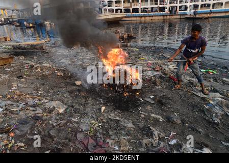 Les gens brûlent des ordures créent de la fumée toxique sur la rive du fleuve Buriganga à Dhaka, au Bangladesh, sur le 19 mars 2022. Dhaka continue d'être classée parmi les villes les plus polluées au monde, avec des débris de construction, des émissions de véhicules et des fours à briques comme principaux contributeurs à la pollution de l'air dans la ville. (Photo par Mamunur Rashid/NurPhoto) Banque D'Images