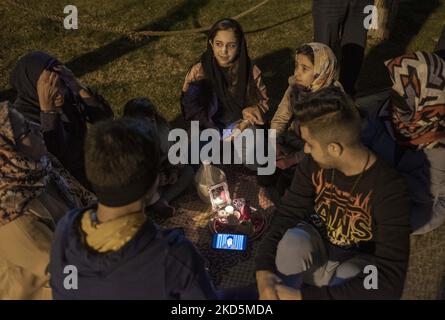 Une famille iranienne s’assoit autour d’un smartphone tandis que l’un d’eux regarde le discours du nouveau an en direct du Guide suprême iranien, l’ayatollah Ali Khamenei, dans le parc aquatique et de pompiers du nord de Téhéran, alors que le nouvel an iranien commence à 20 mars 2022. (Photo de Morteza Nikoubazl/NurPhoto) Banque D'Images