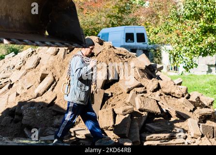 Homme travaillant sur le chantier, devant la pile de blocs de pierre anciens et le godet de pelle hydraulique. Ukraine, Zhytomyr, 12 octobre 2022 Banque D'Images