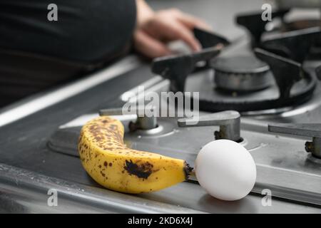 Un œuf et une banane avec des taches noires, placés à côté d'un poêle dans une cuisine colombienne Banque D'Images