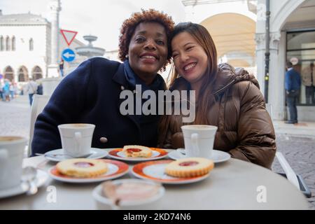 Des amies multiraciales avec un sourire crasseux au bar qui prend le petit déjeuner Banque D'Images